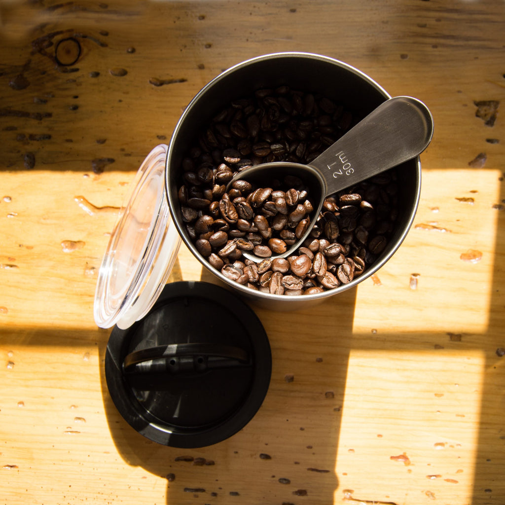 Koffiebonen in een open voorraadbus met maatschep